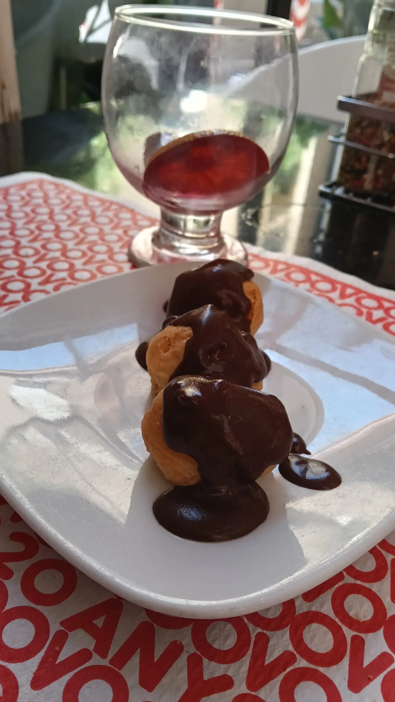 Chocolate-coated profiteroles dessert on a white plate over an OVO-branded placemat, at Ovo.