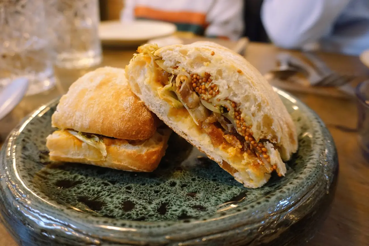 Halved ciabatta sandwich with pulled meat, mustard seeds and cabbage