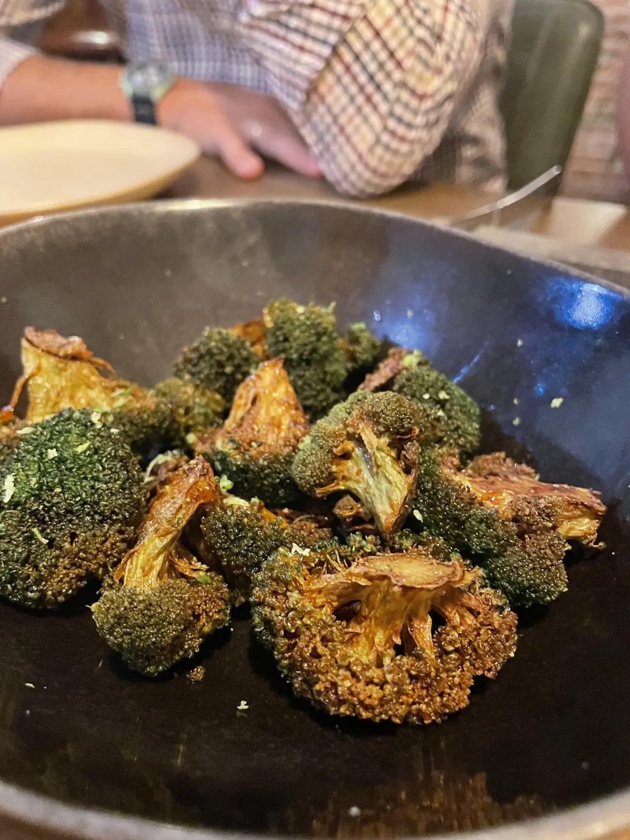 Charred roasted broccoli florets in a dark bowl