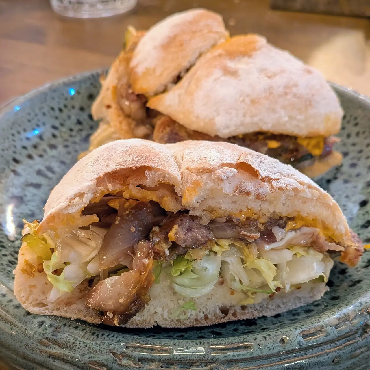 Close-up of two halved sandwiches with grilled meat and cabbage slaw