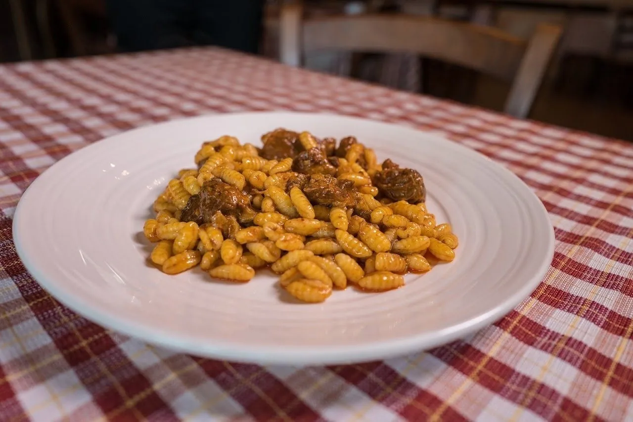 A white plate of small yellow pasta shapes on a red and white checked tablecloth