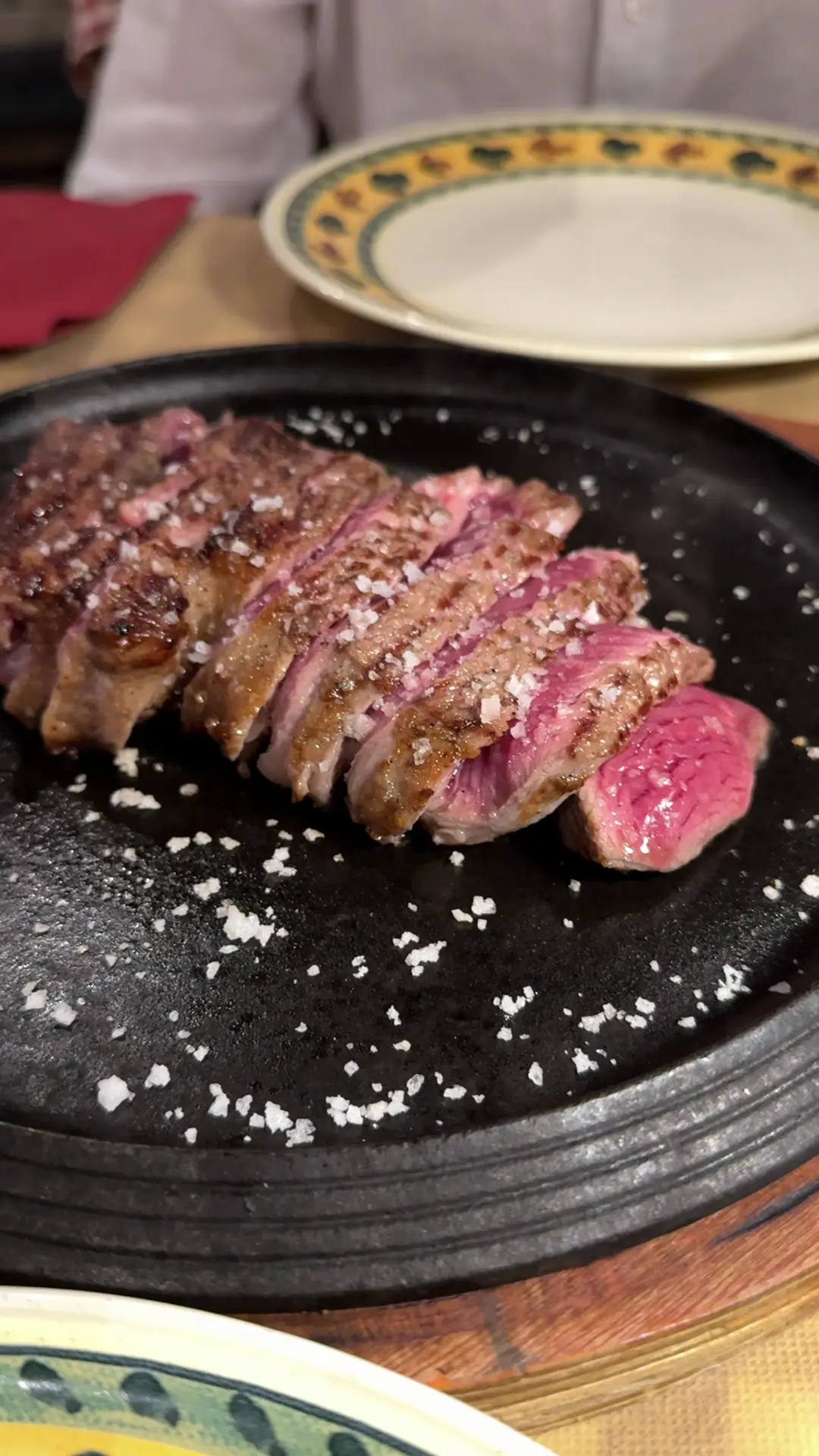 Sliced seared steak on a dark plate with coarse salt