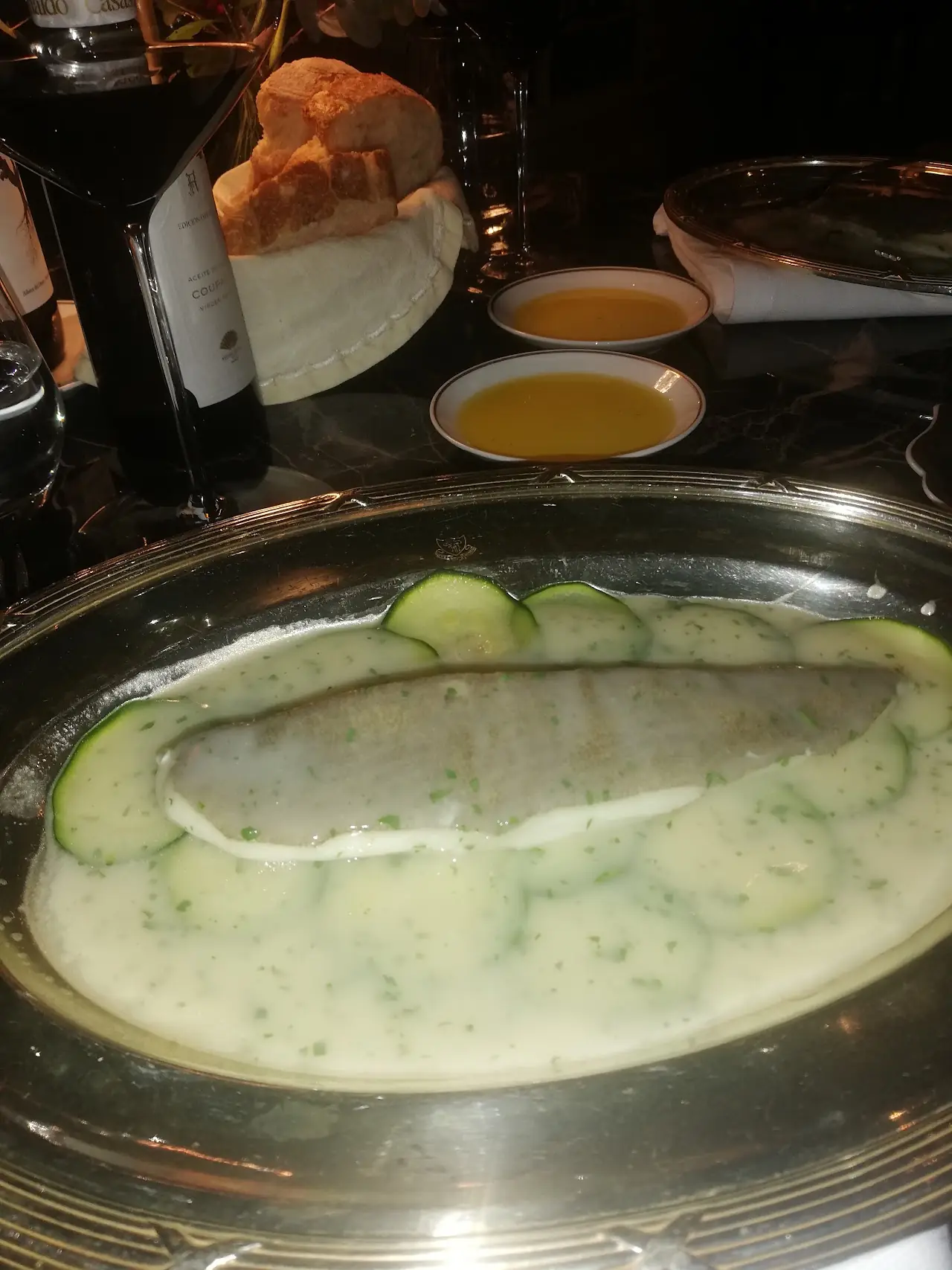 Fish in a pale green sauce on a silver dish