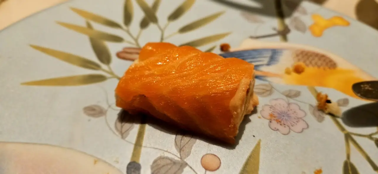 A piece of salmon plated on a decorative floral plate