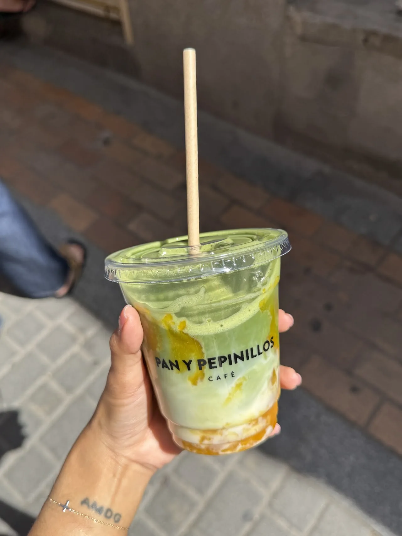 An iced drink with a straw held in someone's hand