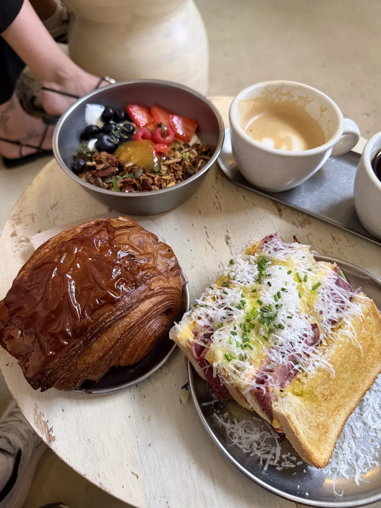 Chocolate croissant and open-faced toast plated together with a coffee