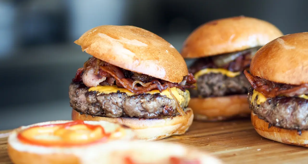 Three bacon cheeseburgers with caramelized onion on a wooden board, Restaurant Parrilla Alfonsina