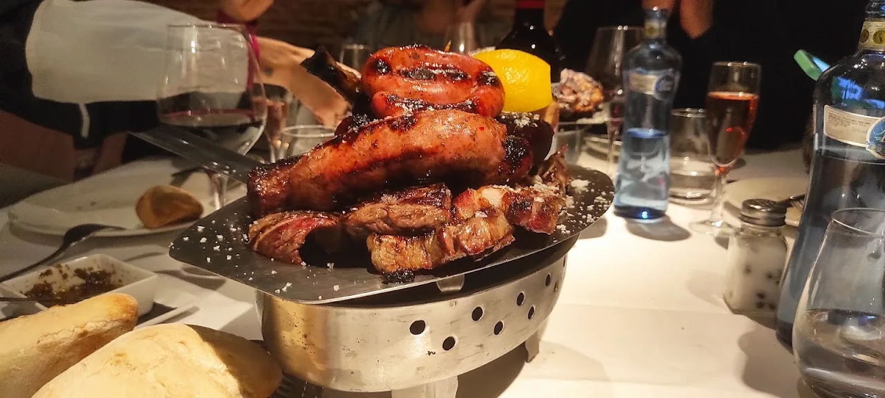 Assorted meats and chorizo grilling on a charcoal parrilla