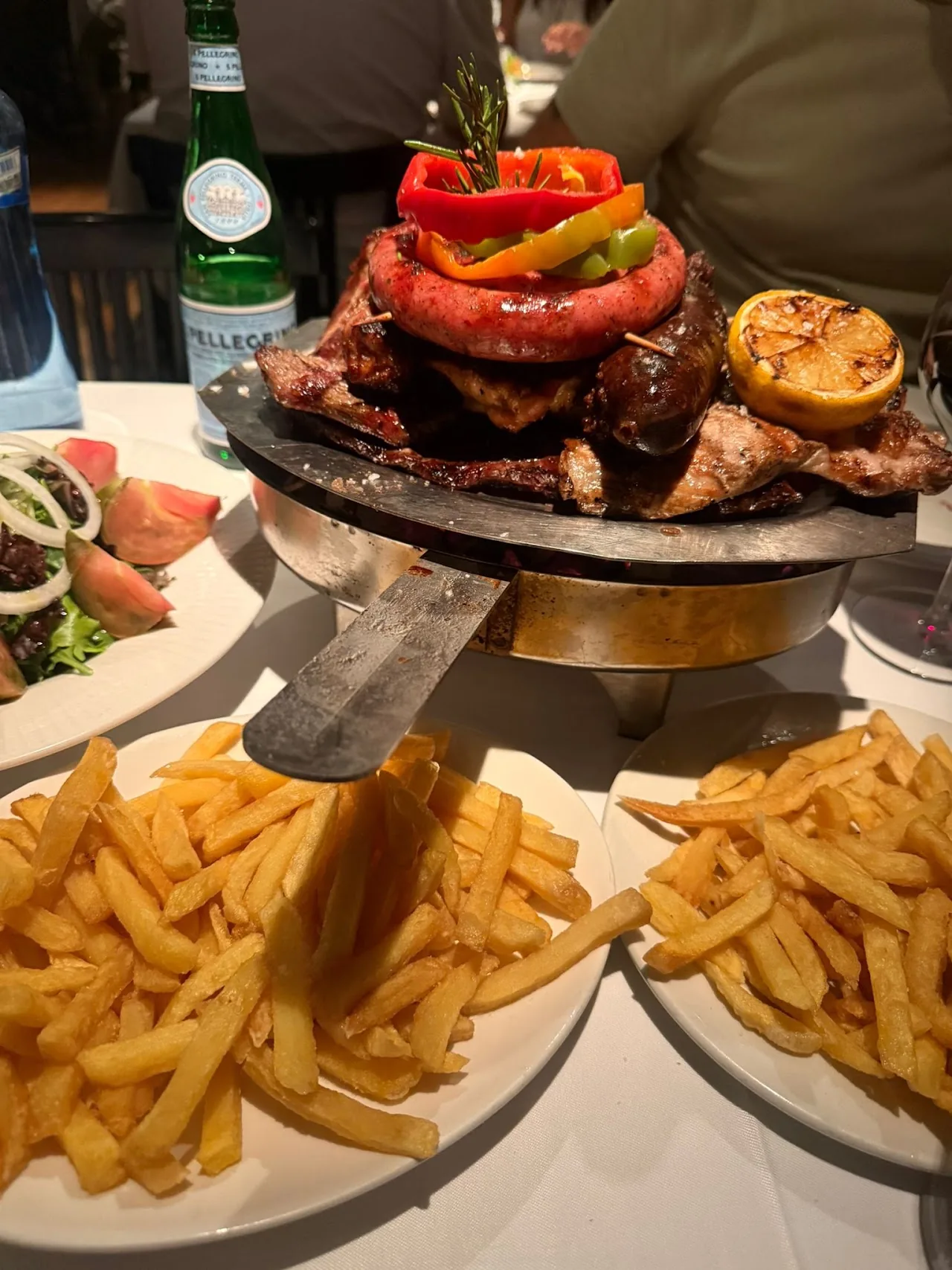 Mixed grill platter with sausage, peppers and a side of french fries