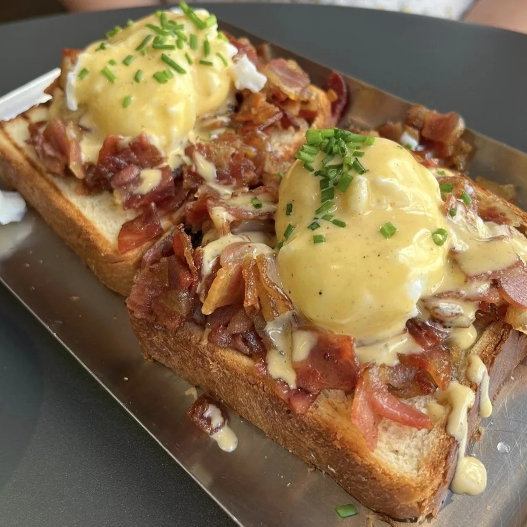 Two slices of toast topped with bacon and poached eggs with hollandaise
