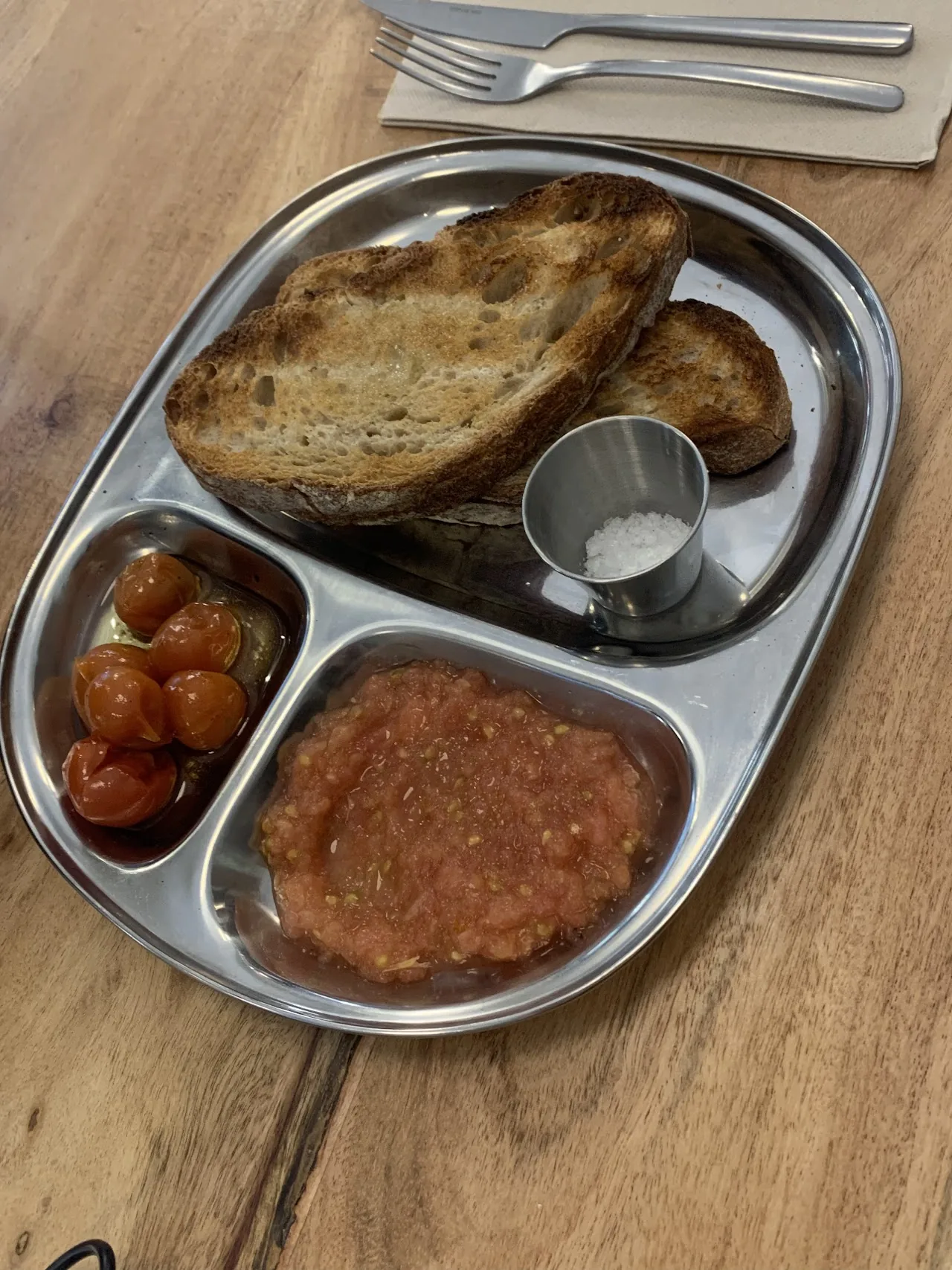 A compartmentalized breakfast tray with toast, jam and a poached egg