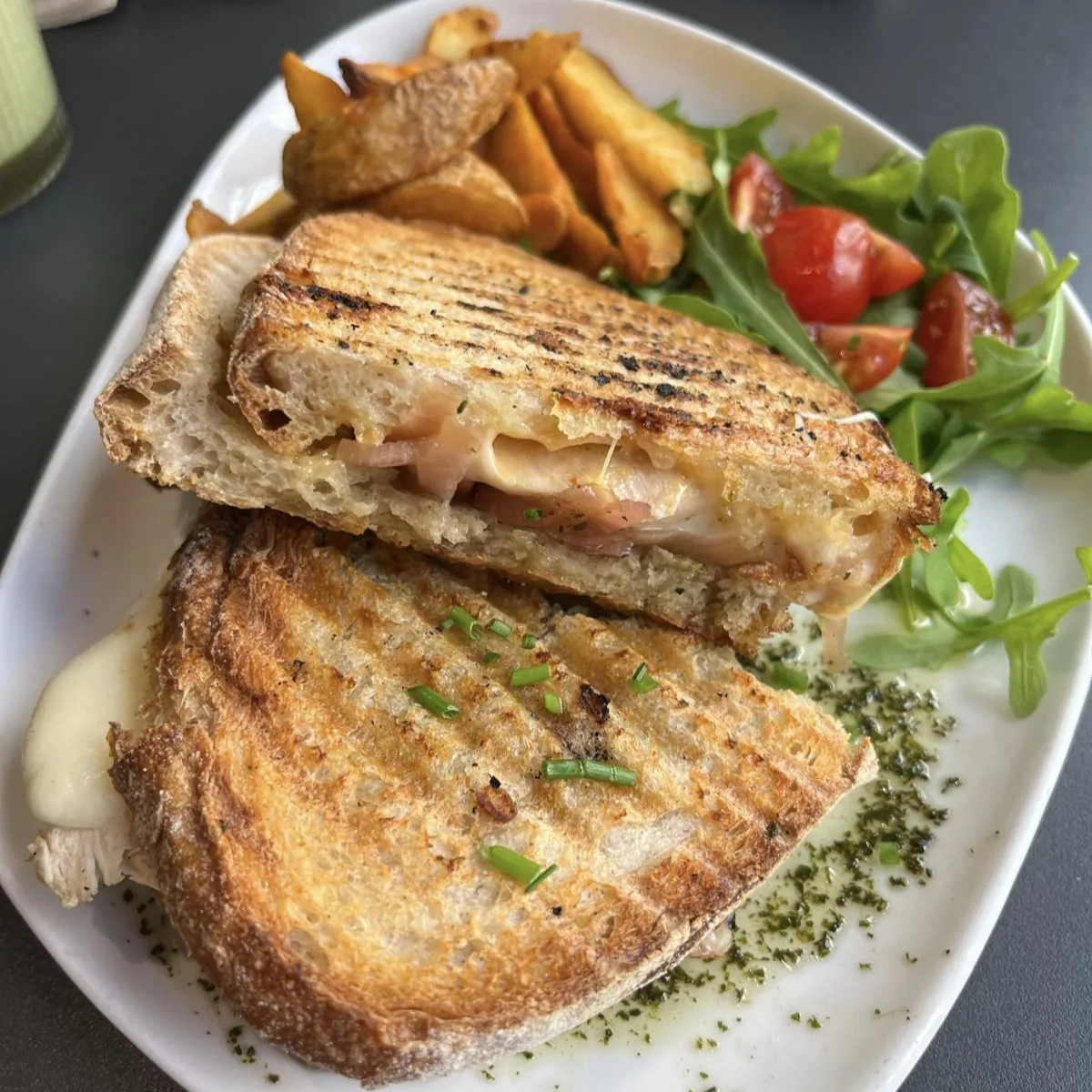 A grilled sandwich cut in half, served with fries and salad