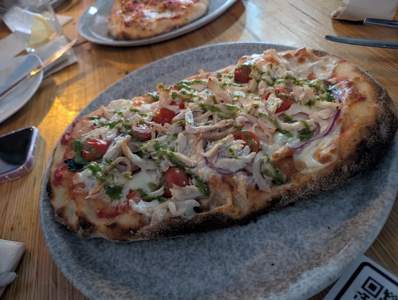 A flatbread pizza topped with tomato, red onion and greens