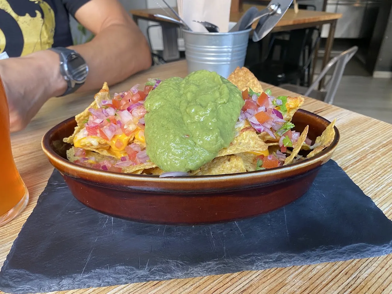 A dish of nachos topped with cheese, pico de gallo and a scoop of guacamole