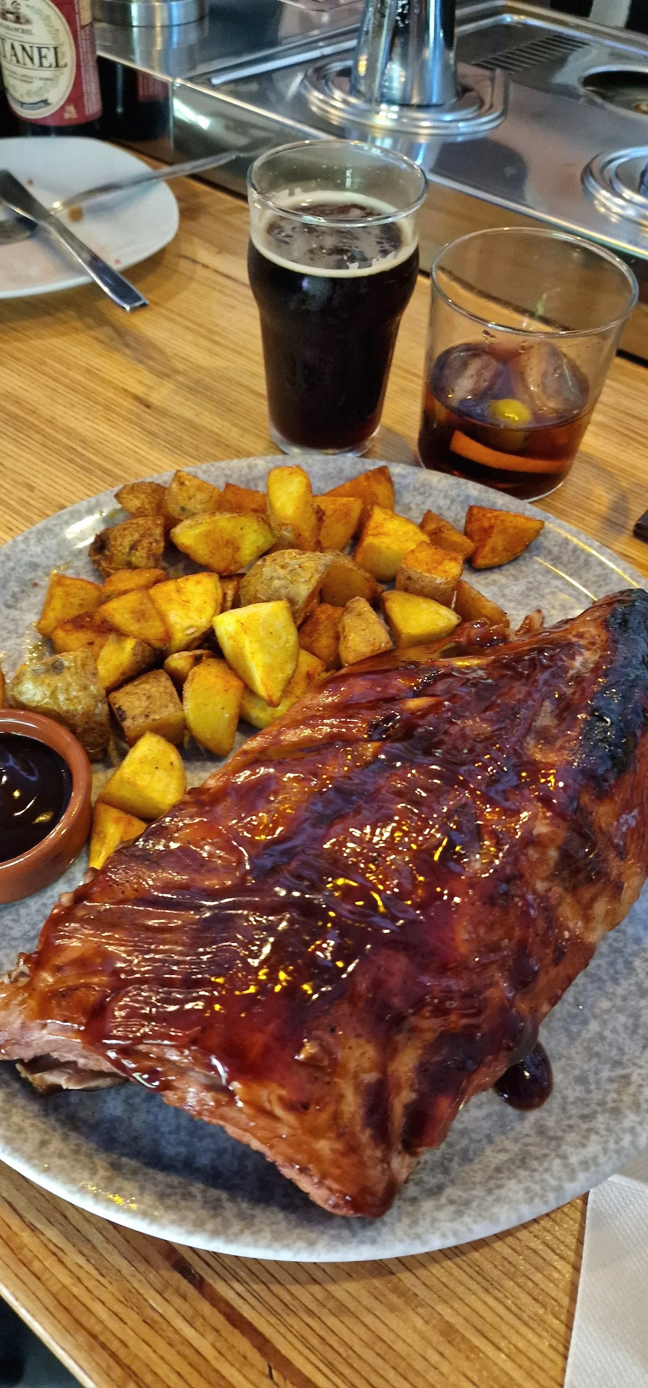 A plate of glazed rack of ribs with roasted potato wedges