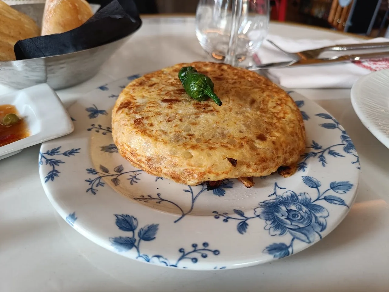 A round Spanish tortilla topped with a sprig of parsley on a plate