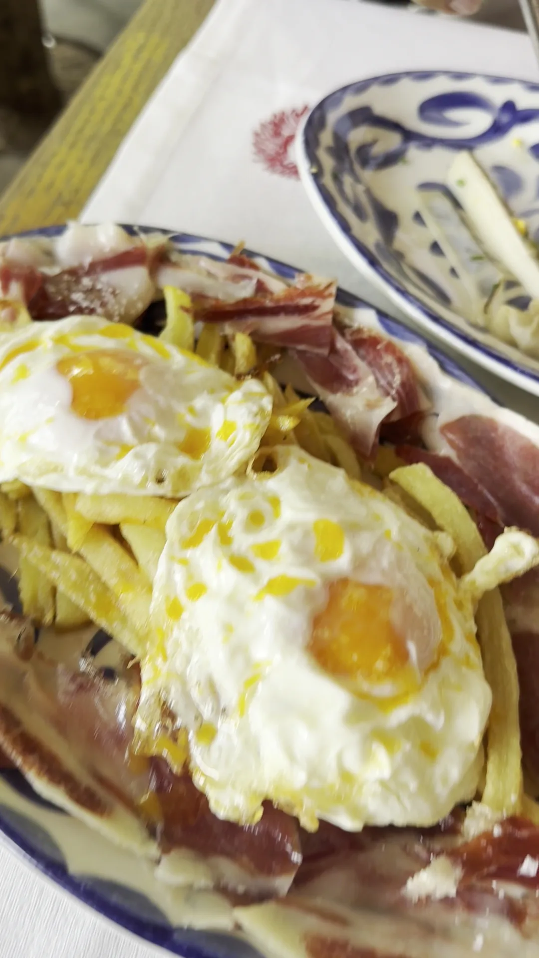 A plate of fried eggs over shredded potatoes with strips of ham