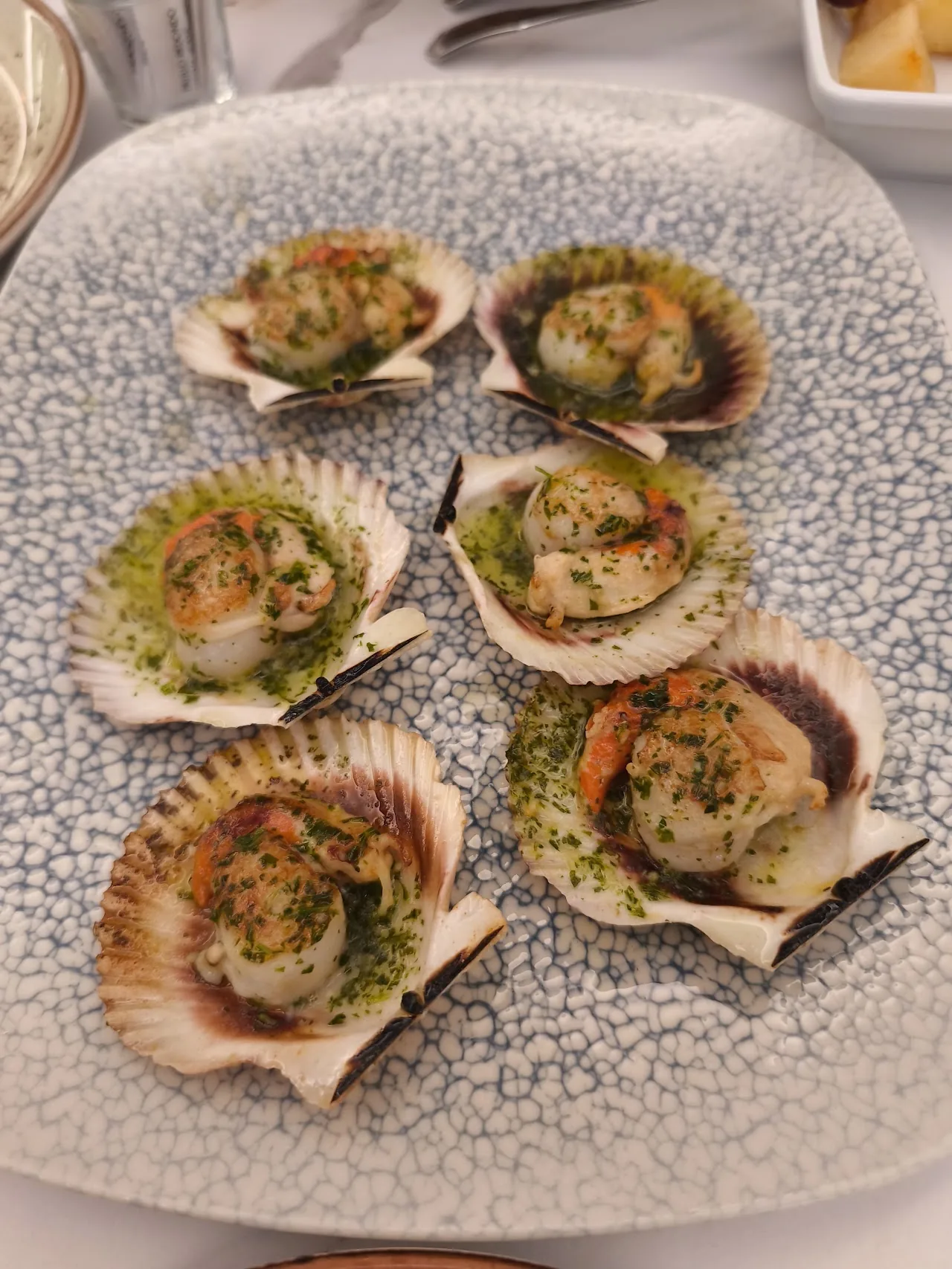 Five scallops on the half shell topped with garlic and herbs