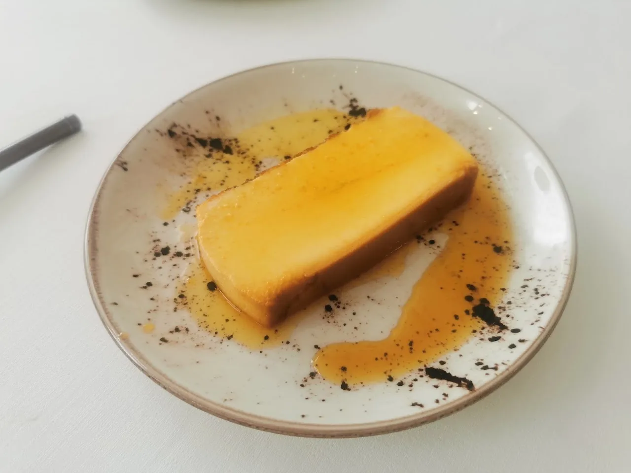 A wedge of flan or custard dessert drizzled with caramel sauce
