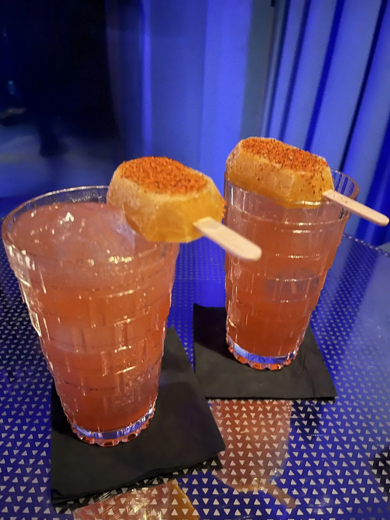 Two cocktails garnished with toasted marshmallows on skewers