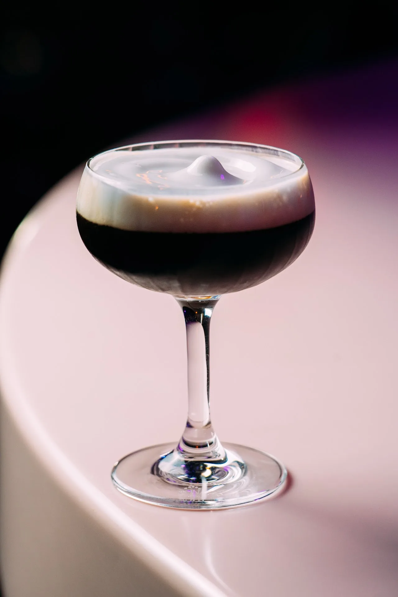 An espresso martini with a frothy top in a coupe glass