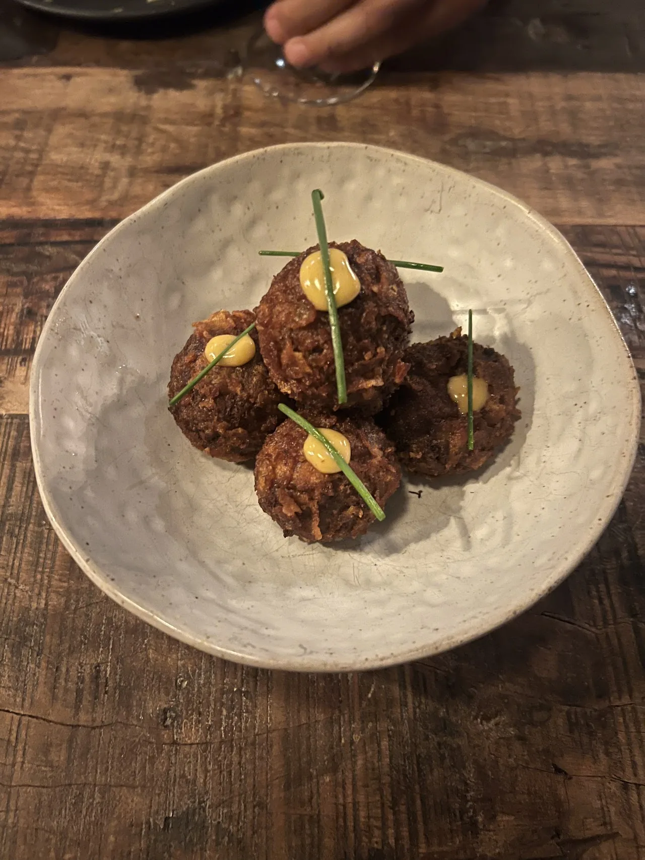 A trio of meatballs plated with dollops of sauce
