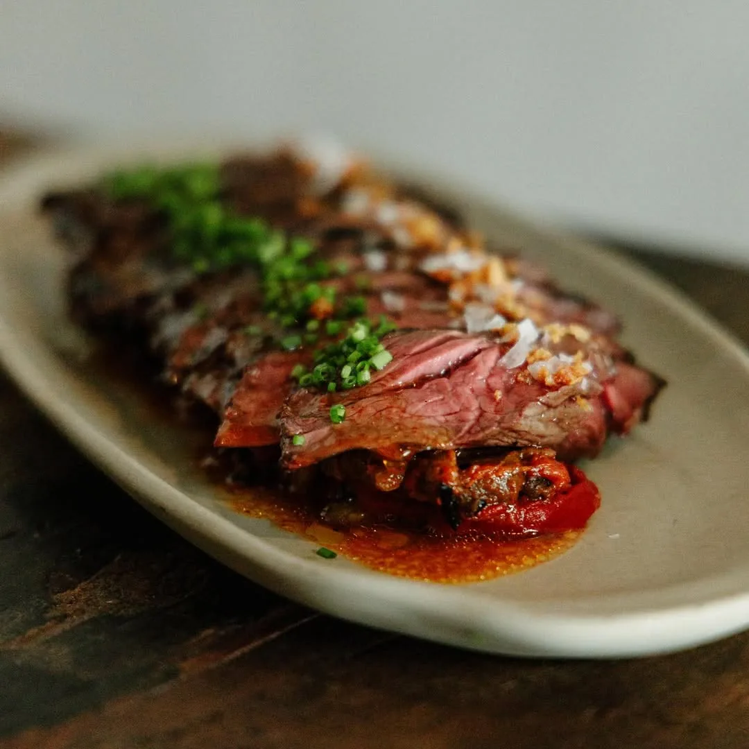 Sliced steak plated with a herb garnish