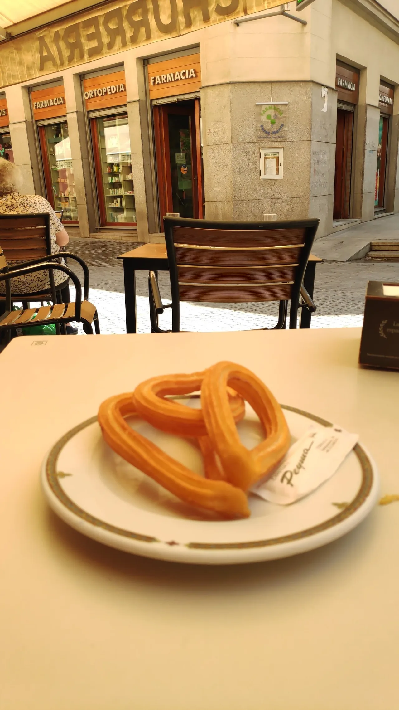 A ring-shaped churro on a plate on a cafe table