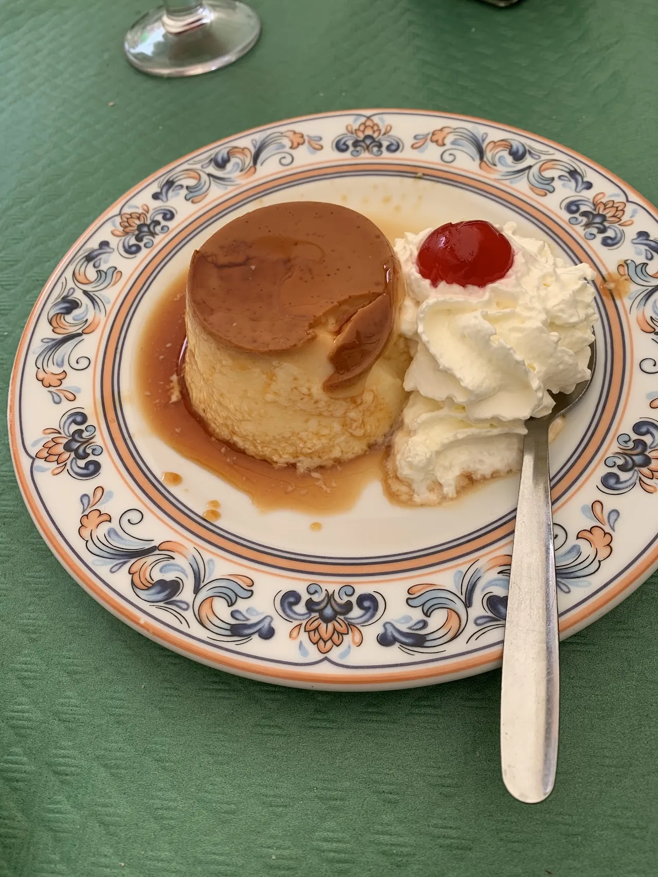 A caramel flan topped with whipped cream and a cherry