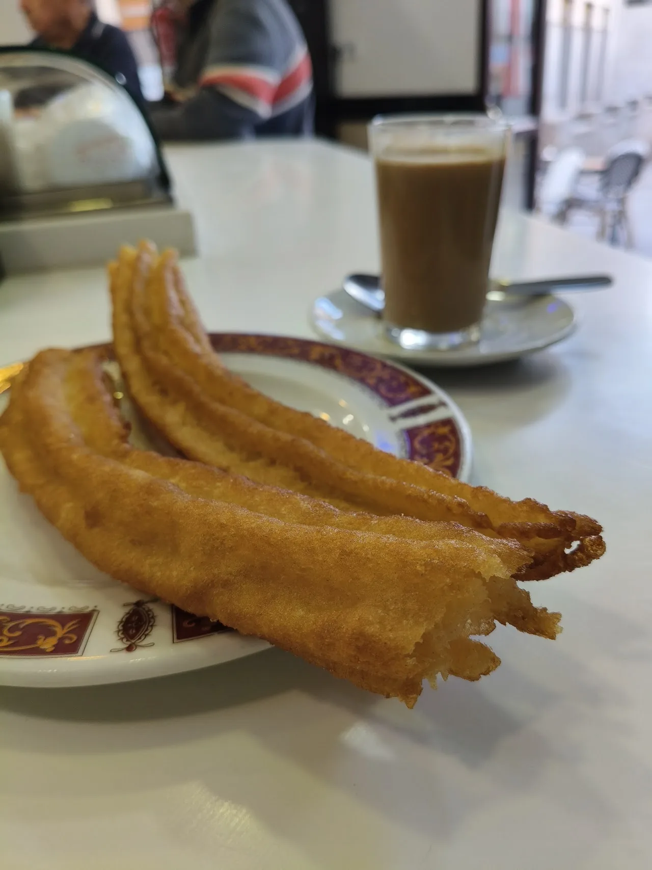 A plate of churros with a cup of coffee