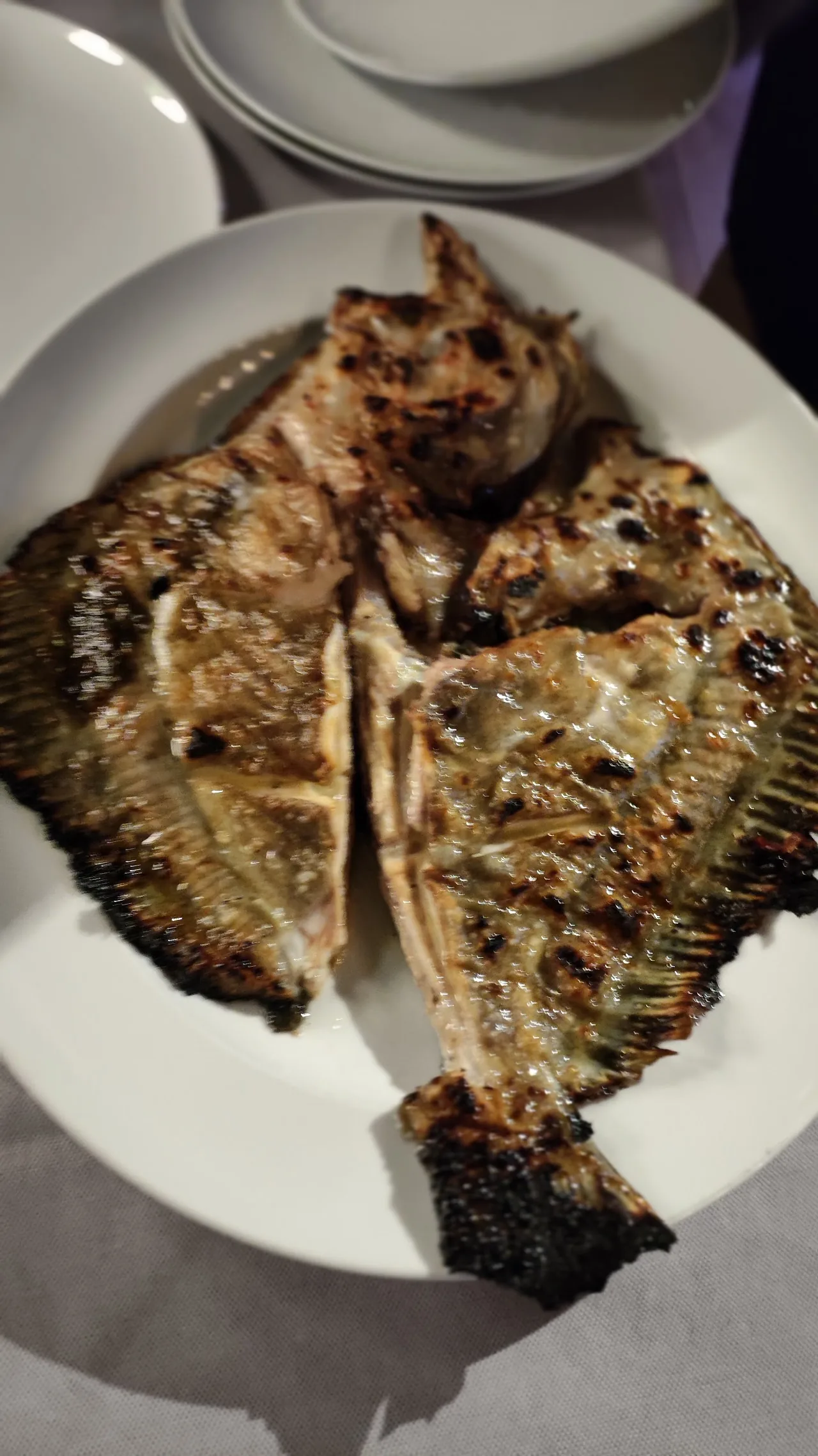 A whole grilled fish split open on a plate