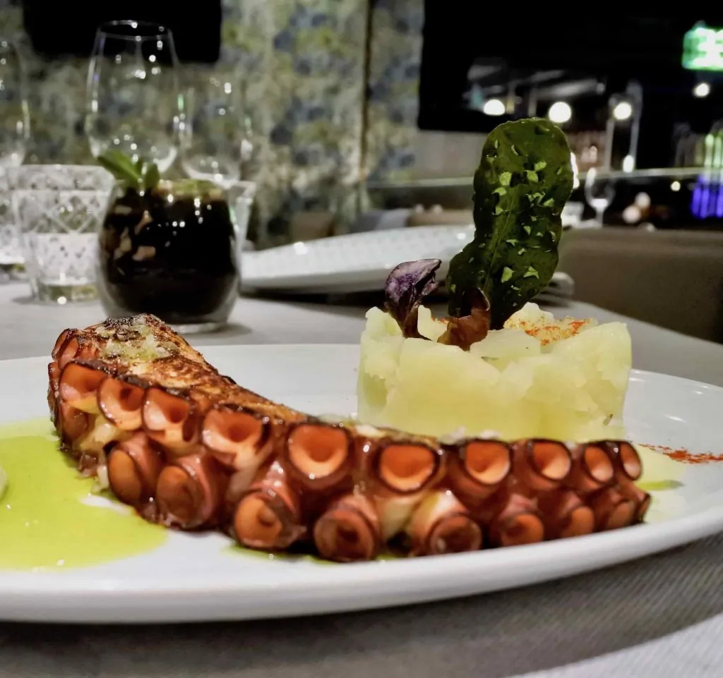 Sliced grilled octopus arranged with a wedge of cheese