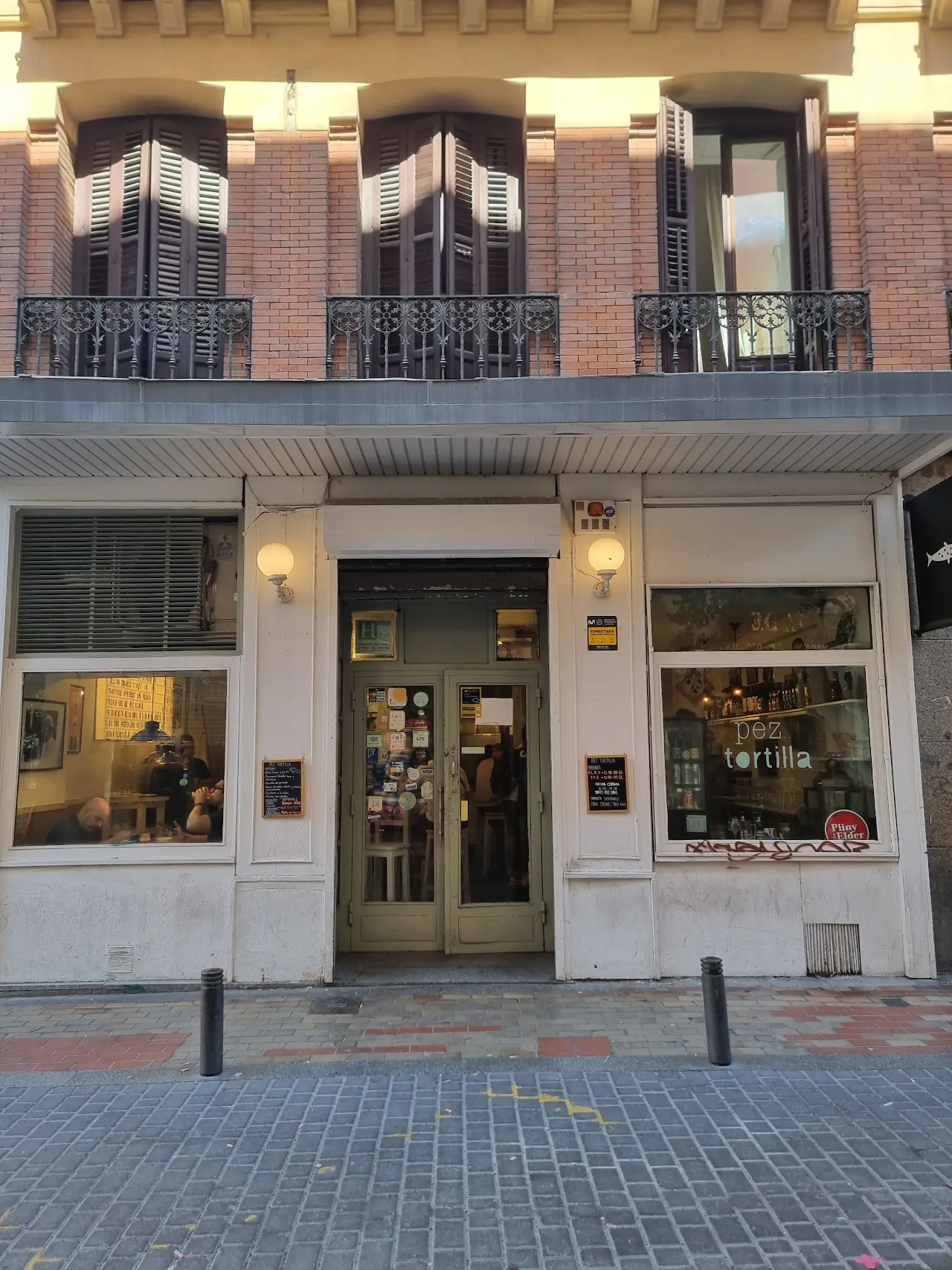 Pez Tortilla's frontage on Calle del Pez, with wooden doors and lamps under the balconies