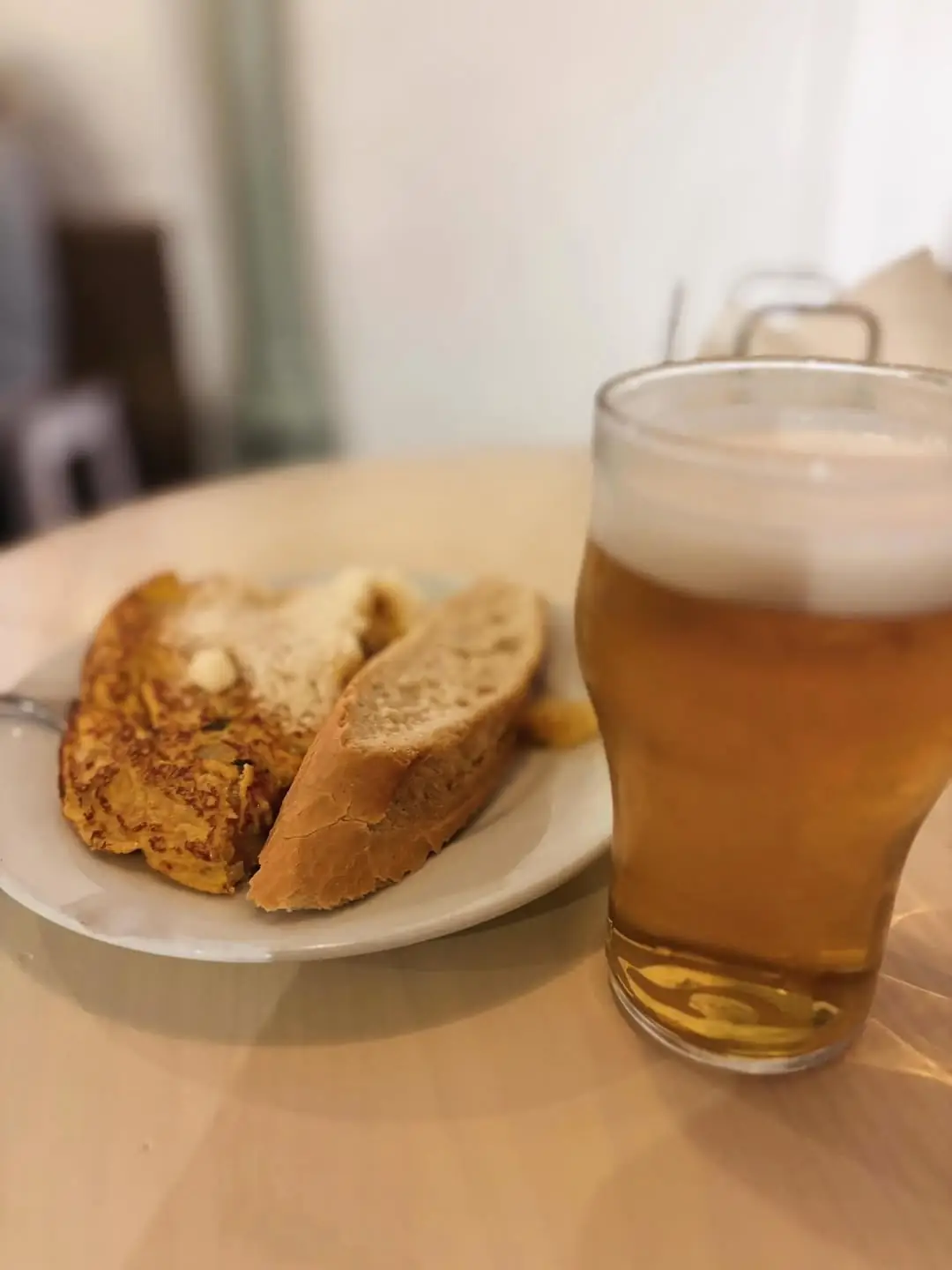Tortilla slice and bread on a plate next to a glass of beer