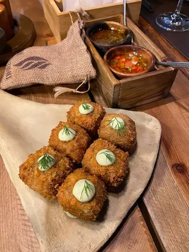 Breaded croquettes topped with herb sprigs, with dipping sauces