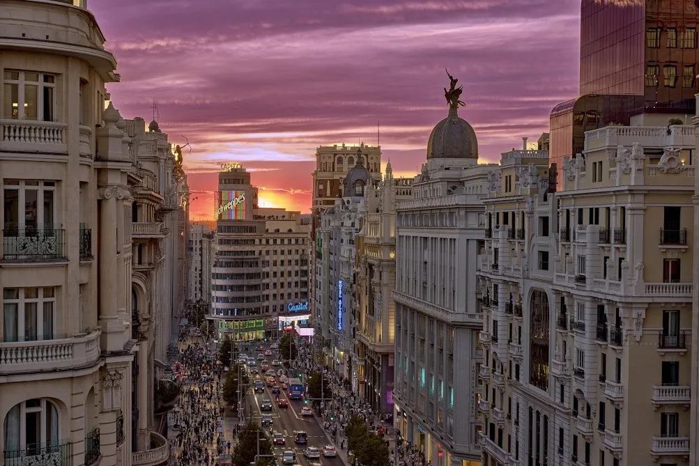 A sunset sky over Madrid buildings and a busy street seen from above
