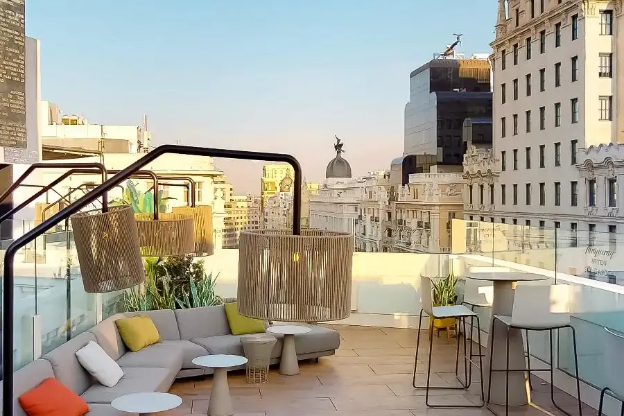 Rooftop terrace lounge seating with sofas, plants, and city skyline view at golden hour