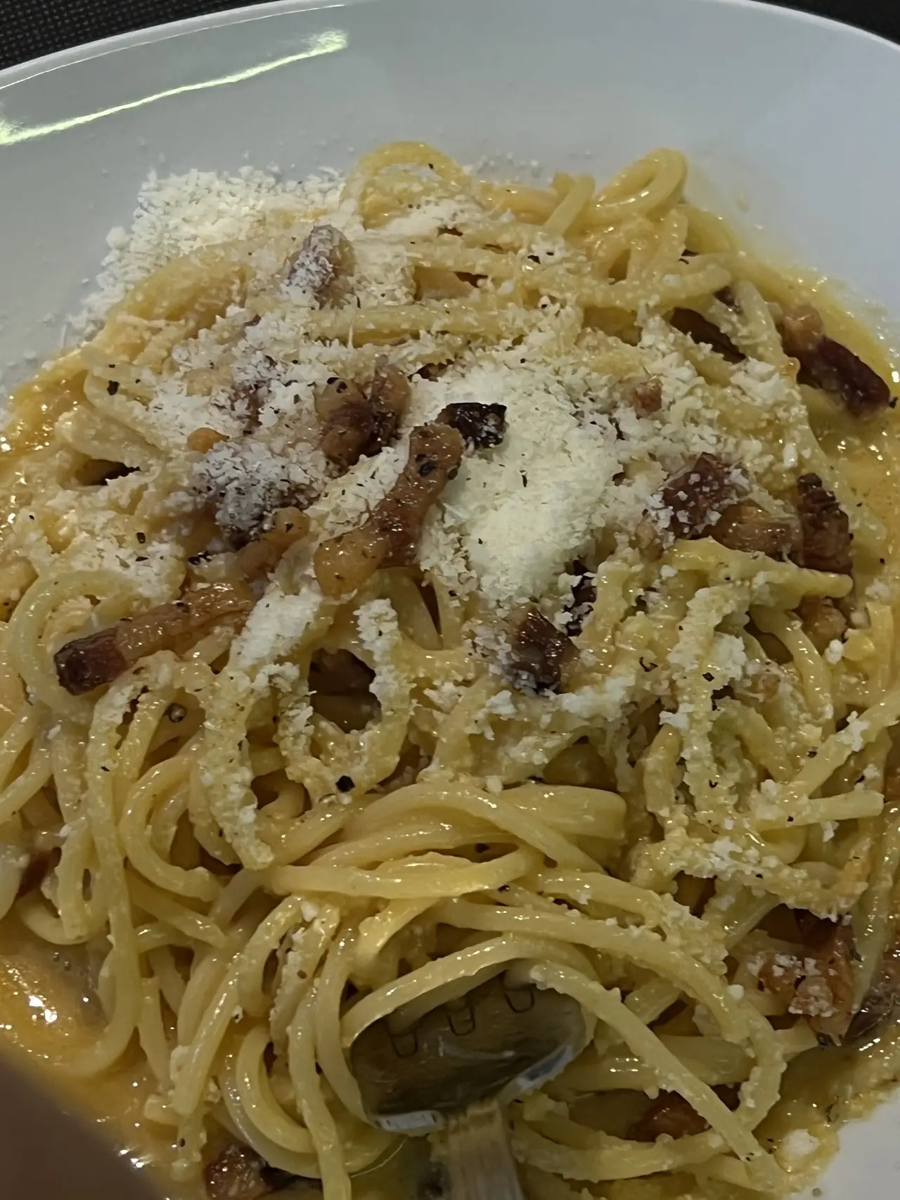 Spaghetti carbonara with crisp pork pieces and grated cheese