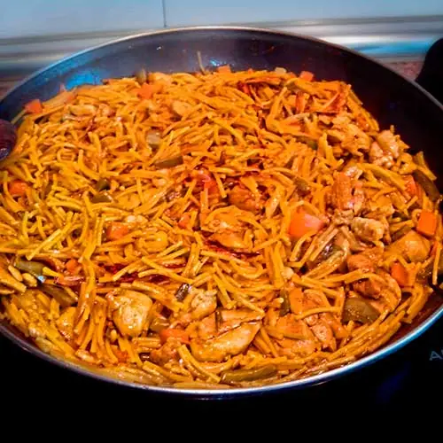 Fideuà noodles cooked with chicken and vegetables in a large paella pan, Piolindo