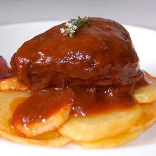 Braised meat cheeks in a thick reduced sauce over sliced roasted potatoes, Piolindo