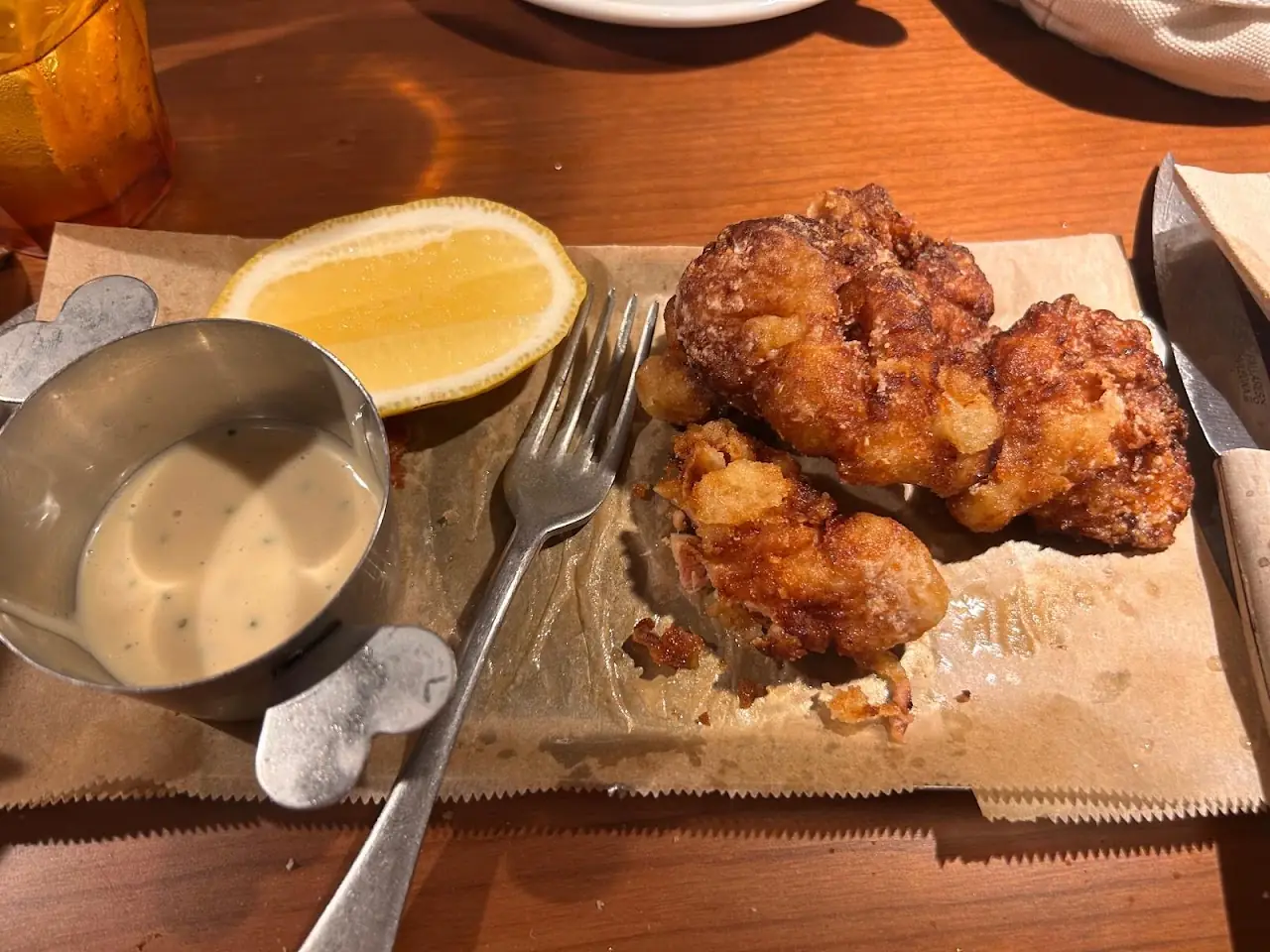 Fried chicken bites with a creamy dipping sauce and a lemon wedge on a paper-lined board, at Piropo Bistro.