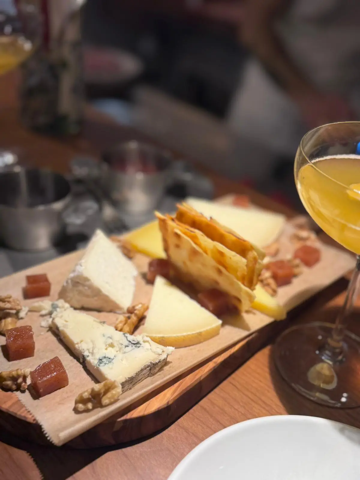 Wooden board of assorted cheeses with walnuts and honey served with drinks, at Piropo Bistro.