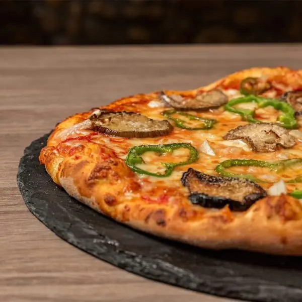 Pizza topped with cheese, aubergine slices and green pepper rings on a slate board