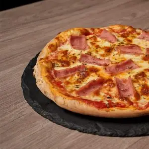 Ham and cheese pizza on a round slate board over a wooden table