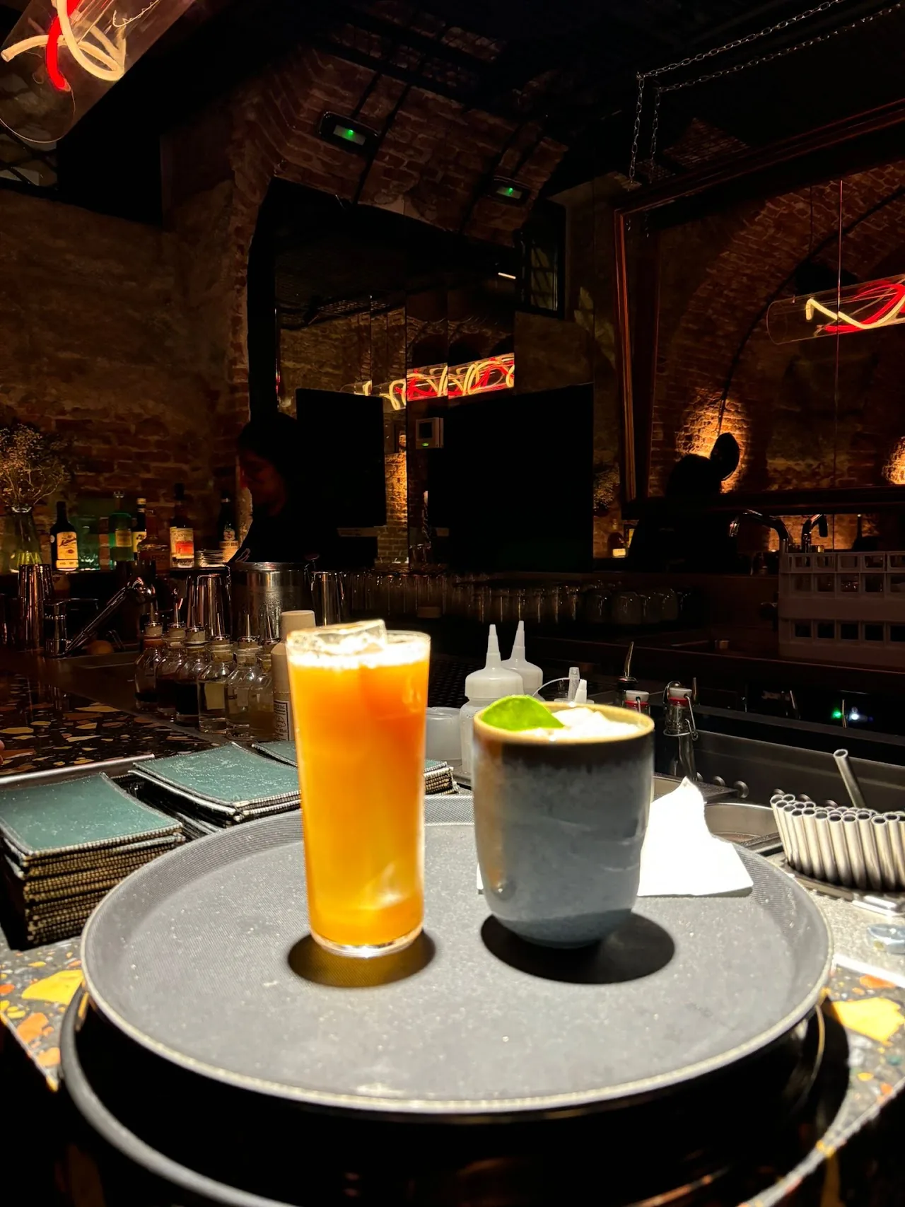 A tray with an orange cocktail and a white frothy drink