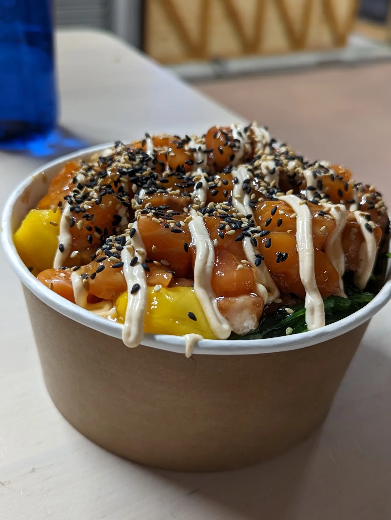 A poke bowl drizzled with sauce and topped with black sesame seeds