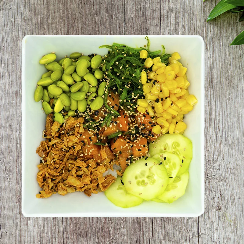 A poke bowl with edamame, corn, cucumber, and marinated tuna in separate sections