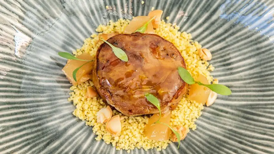 Seared foie or pate over couscous with fruit compote and herb garnish