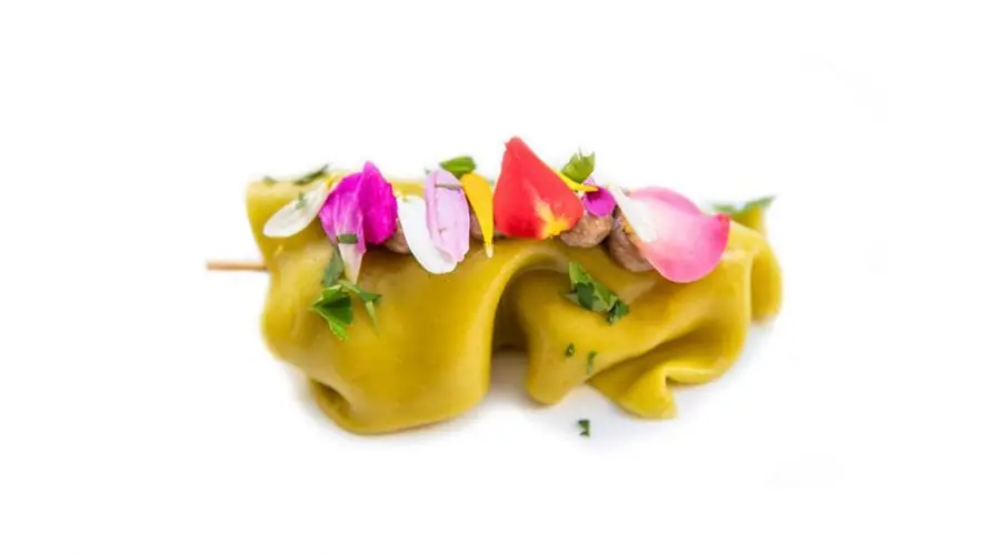 Green pasta parcel skewer topped with edible flower petals and herbs