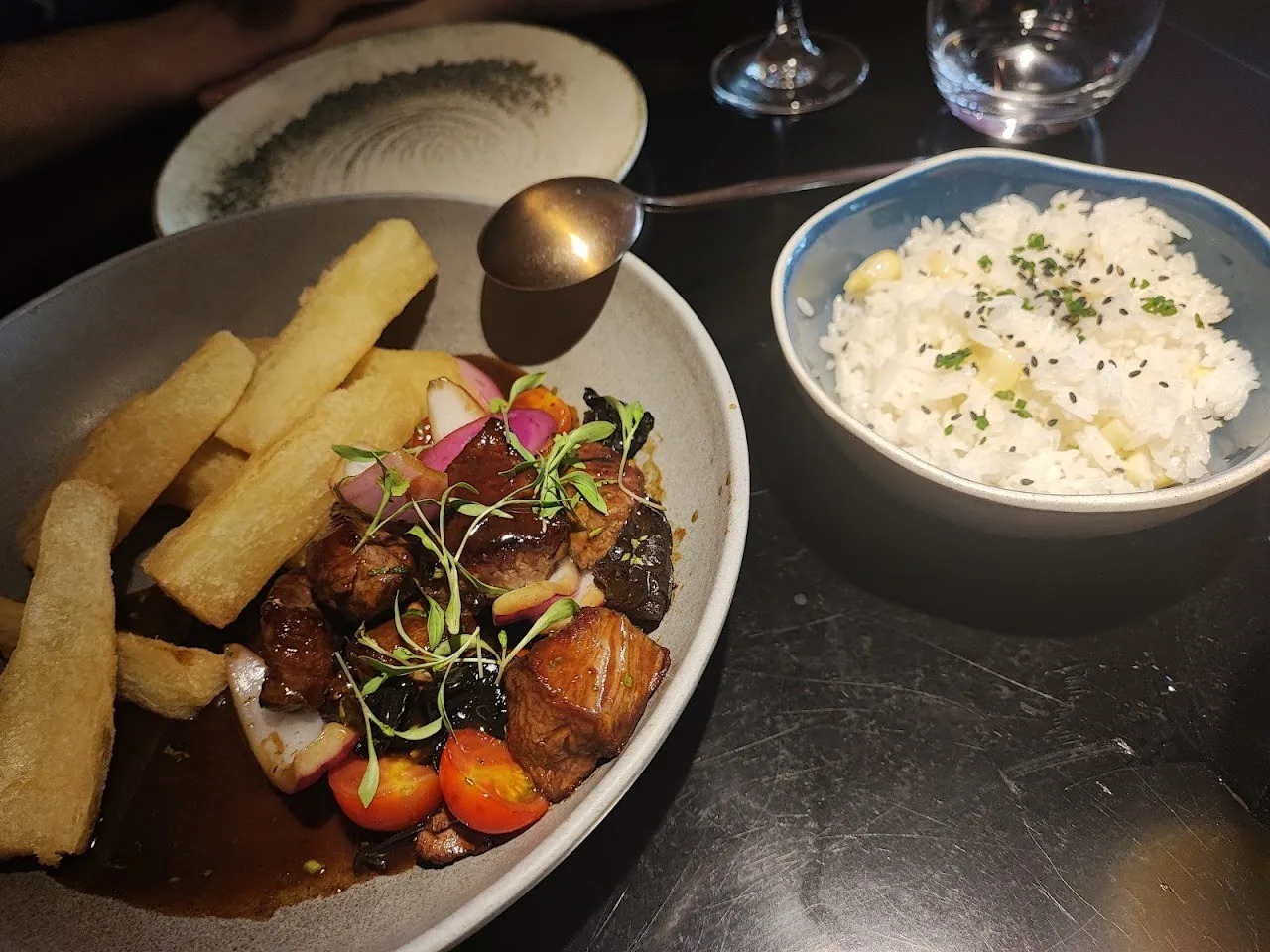 Strips of stir-fried beef with fries in a dark sauce next to a bowl of white rice